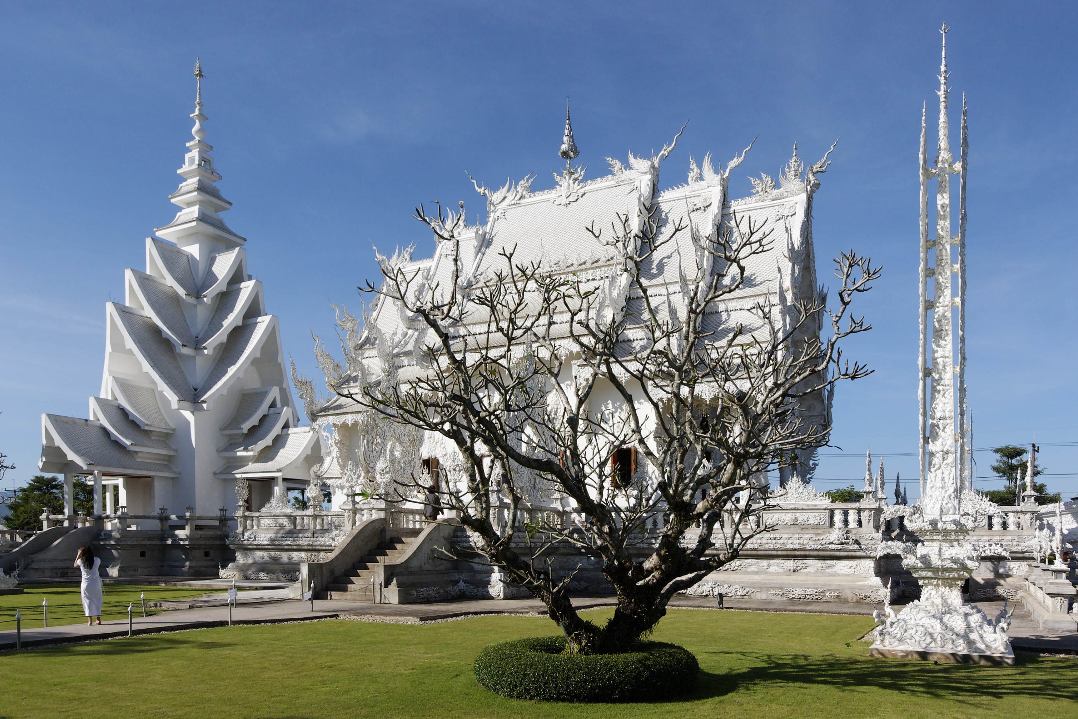 The White Temple grounds with white spires and a tree on the lawn under a blue sky